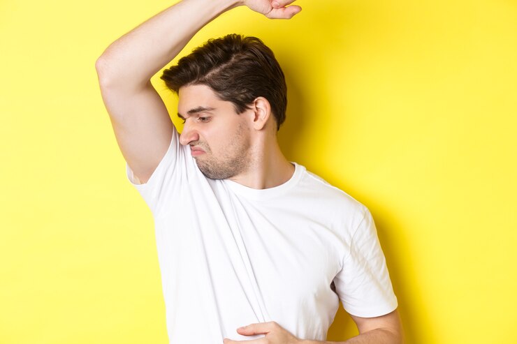 man sweat smelling his armpit standing white t shirt grimacing from stinky clothes 1258 41065